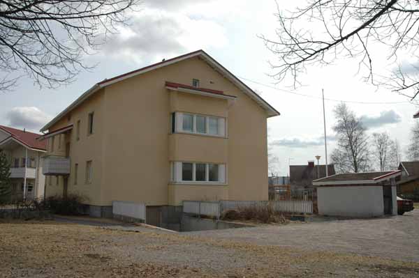 Asuinkerrostalo, kerrarissa autotalli. Pihalla lapekattoinen roskakatos.&nbsp;(Minna Pesu&nbsp;3.5.2005)