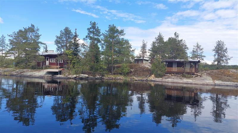 Yleisnäkymä kohti kohdeluotoa, jossa asuinrakennus oikealla, sauna vasemmalla ja talousrakennus niiden takana.&nbsp;(Dan Ronimus&nbsp;5/2022)