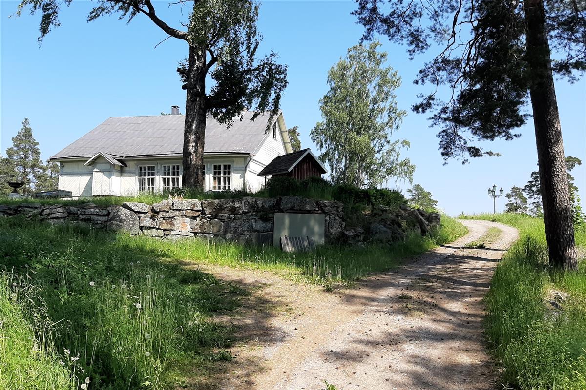 Näkymä Ruhtinaan majan pihapiiriin etelästä päin kuvattuna. Kivipengerryksessä on kulkuaukko maakellariin.&nbsp;(Esa Hertell&nbsp;17.6.2020)