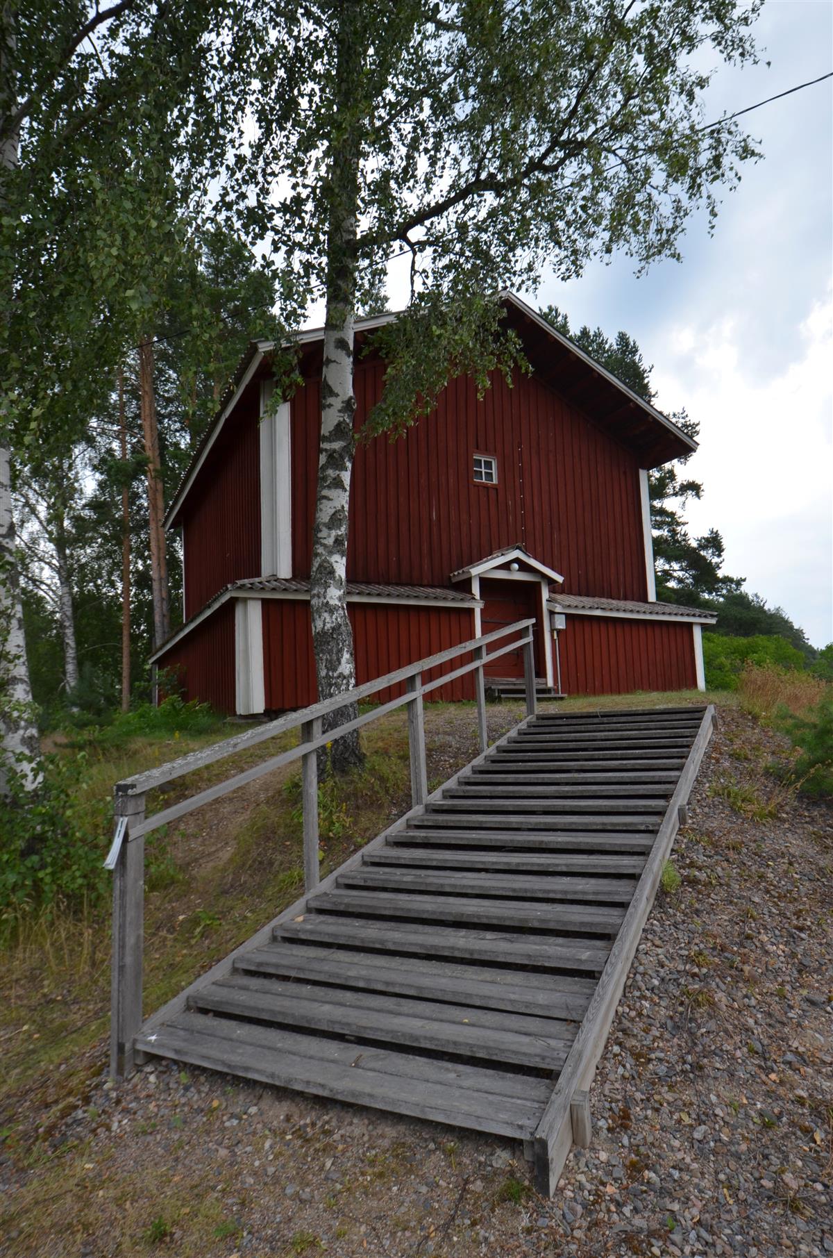 Taipalsaaren lainajyvästön makasiini lännestä päin kuvattuna. Etualalla mäelle johtava portaat.&nbsp;(Päivi Makkonen&nbsp;2025)