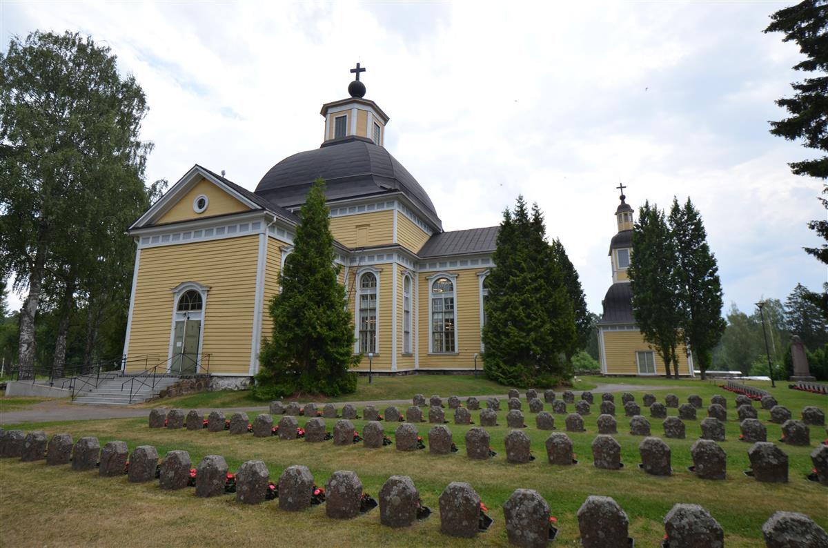 Taipalsaaren kirkko ja kellotapuli lännestä päin kuvattuna. Etualalla sankarihautausmaa.&nbsp;(Päivi Makkonen&nbsp;2025)